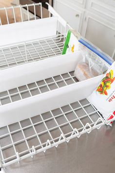 an open refrigerator door with some food in the bottom drawer and another bag on the bottom shelf