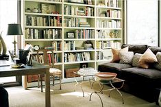 a living room filled with lots of furniture and bookshelves next to a window