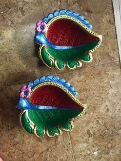 two red and green vases sitting on top of a tile floor