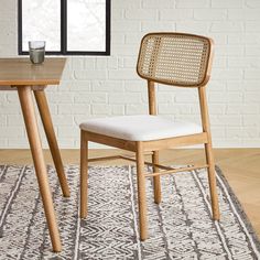 a chair and table in front of a window with a rug on the floor next to it