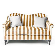 an orange and white striped couch with two pillows on top of the armrests