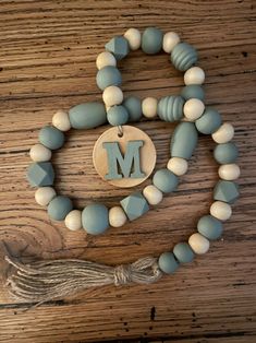 a beaded necklace with a wooden letter m on it