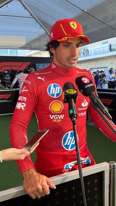 a man in a red suit and cap speaking into microphones at a press conference