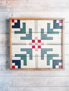 a wooden wall hanging on the side of a white wood planked wall with an abstract design