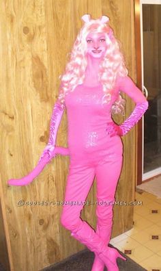 a woman dressed in pink is standing next to a wooden wall and wearing a cat costume