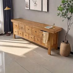 a wooden bench sitting next to a potted plant on top of a hard wood floor