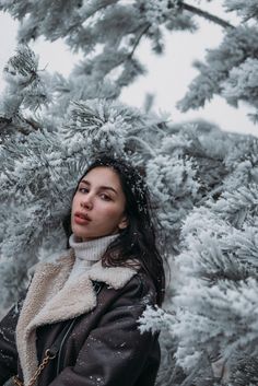 a woman standing in front of a tree covered in snow