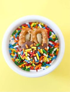 a bowl filled with donuts and sprinkles on top of a yellow background