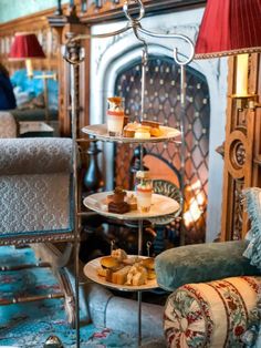 three tiered trays with pastries on them in front of a fireplace