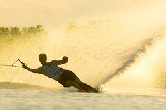 a man riding skis while being pulled by a boat in the water on a sunny day