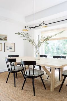 a dining room table with six chairs and a rug on the floor in front of it