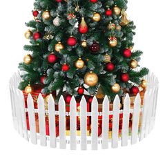 a small christmas tree in a wooden box with ornaments on it and a white picket fence