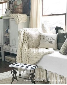 a white bed sitting next to a window in a room with lots of pillows on top of it