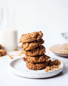 a stack of cookies sitting on top of a white plate next to a glass of milk