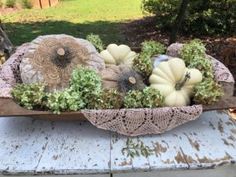 an arrangement of pumpkins and gourds in a wooden bowl on a table