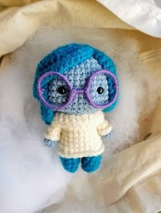 a small crocheted doll with glasses on it's head