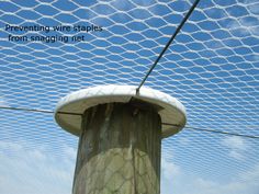 a close up of a wooden post with a net on top and sky in the background