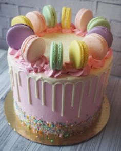 a pink cake with macaroons and sprinkles on the icing