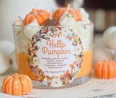 an orange and white dessert in a glass container with pumpkins around it on a table