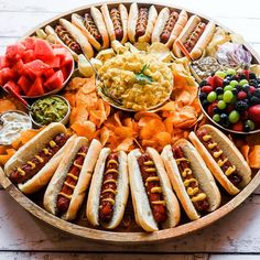 a platter filled with hot dogs, chips and fruit