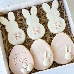 three decorated cookies in a box with the words happy easter written on them and bunny ears