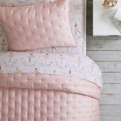 a pink bed with ballet themed sheets and pillows