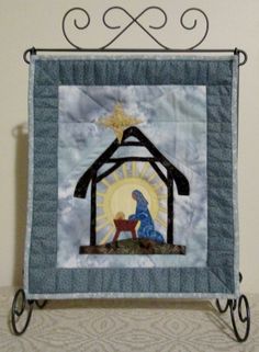 a quilted nativity scene with a star on the top and a blue frame