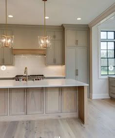 a large kitchen with an island in the middle and two lights hanging from the ceiling