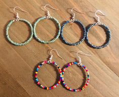 four pairs of beaded hoop earrings sitting on top of a wooden table