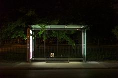 an empty bus stop at night with the lights on and no one in it yet