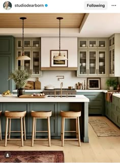 an image of a kitchen setting with green cabinets and stools on the counter top