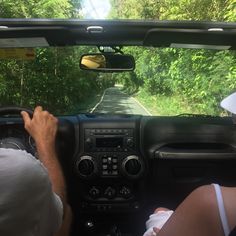 two people in the driver's seat of a vehicle driving down a country road