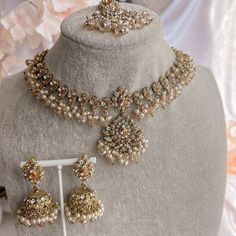 a necklace and earring set on display in a shop window, with flowers behind it