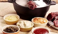 several different types of food in bowls on a table next to an open slow cooker