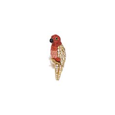 a red bird brooch sitting on top of a white surface