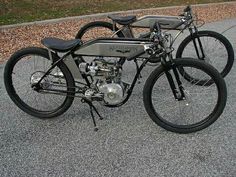 two motorcycles parked side by side on the street with grass in the backgroud