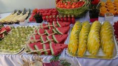 many different types of fruits and vegetables are on display at a buffet table with white linens