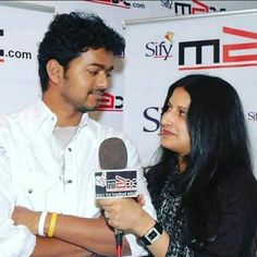 a man holding a microphone next to a woman in front of a sign that says sify tv