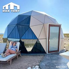 a woman sitting on a chair in front of a geoglyic dome with the door open