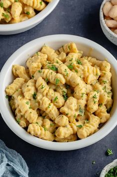 two bowls filled with macaroni and cheese on top of a blue tablecloth