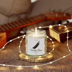 a candle sitting on top of a wooden table next to a guitar and some string lights