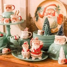 a table topped with plates and cups filled with santa clause figurines next to other christmas decorations