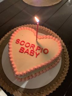 a heart shaped cake with a lit candle in the shape of a baby's name