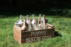 a crate filled with bottles sitting on top of a lush green field