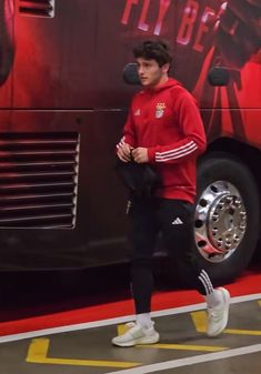 a young man is walking in front of a bus