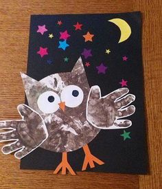 an owl made out of paper on top of a wooden table with stars and moon in the background