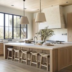 a large kitchen with wooden cabinets and stools next to an island in the middle