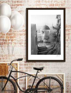 a black and white photo hanging on a brick wall above a bicycle with balloons in front of it