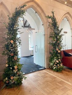 an archway with flowers and greenery on the wall next to a red couch in a room