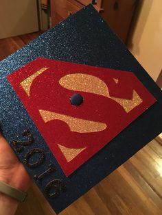 someone is holding up a graduation cap with a superman symbol on it